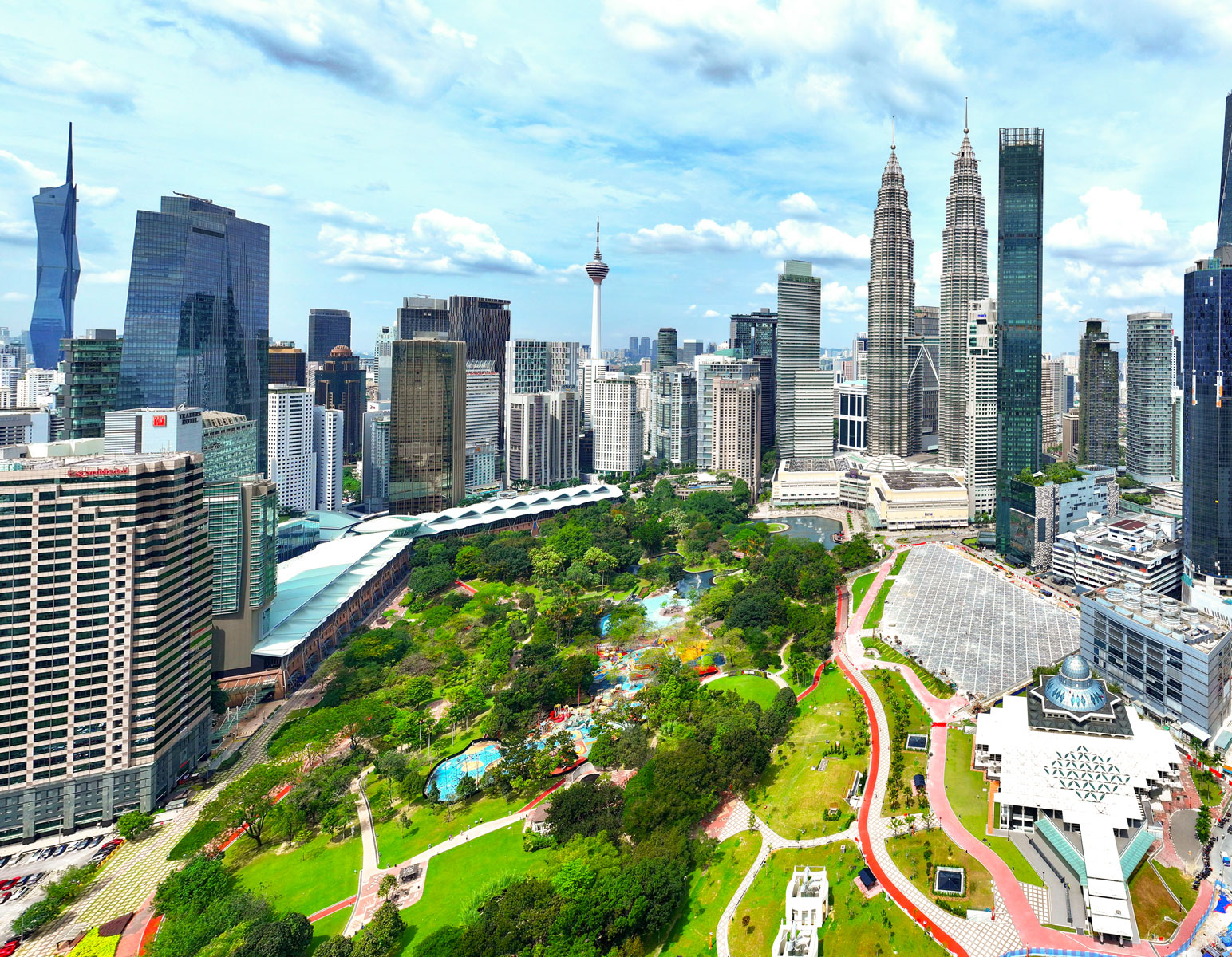 Kuala Lumpur skyline featuring the Petronas Twin Towers and KL Tower, surrounded by urban skyscrapers, green parkland, and vibrant cityscape