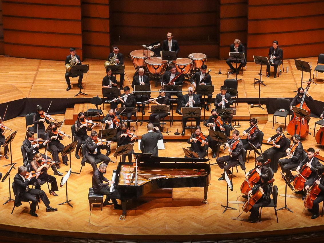 Symphony orchestra performing on a grand stage, showcasing art, lifestyle & heritage in a professional concert hall